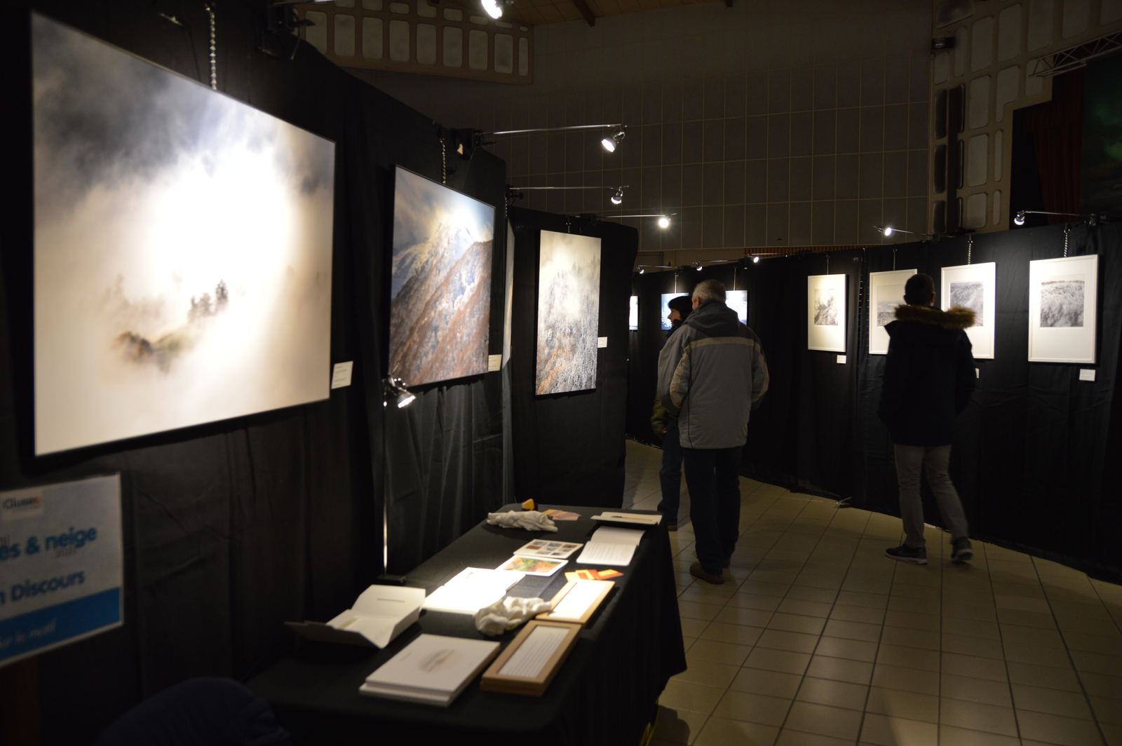 Visitors walking among large framed prints of snowy landscapes.