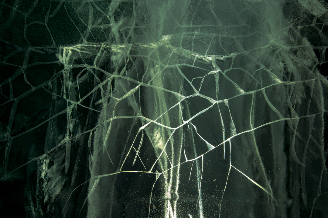 A network of cracks in the ice, in greens and greys.